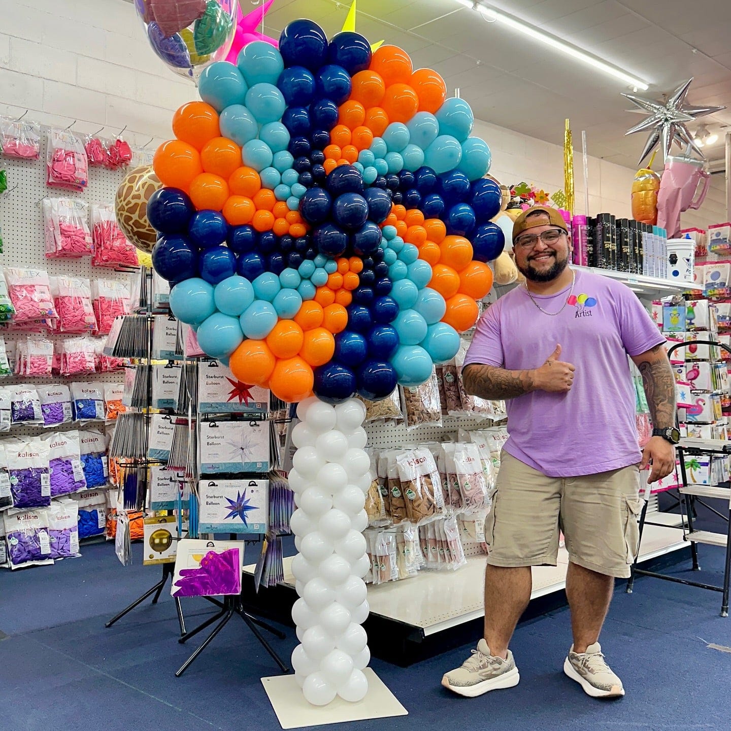 Man standing next to a colorful balloon design in a store.